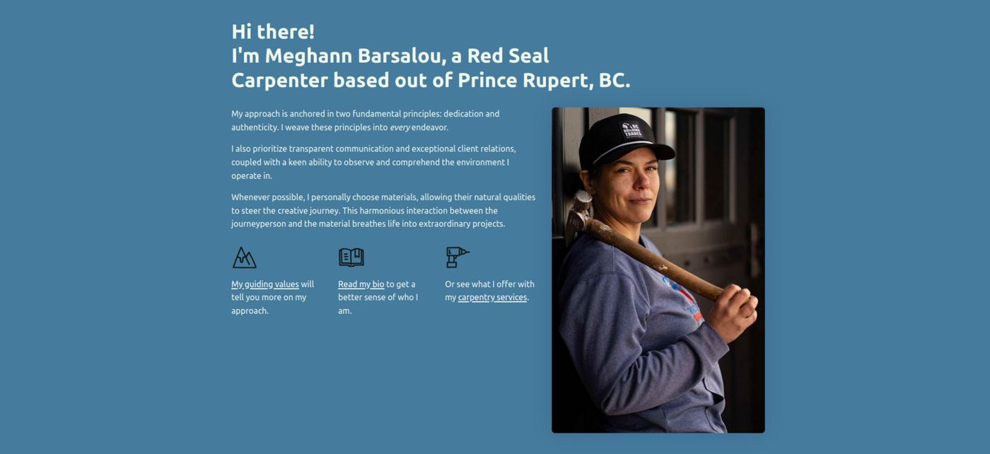 Carpenter Meghann with a hammer, next to a brick wall.